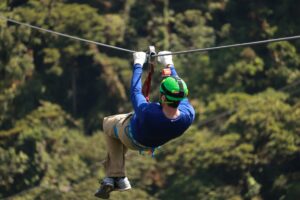 man in blue shirt and green helmet ziplining