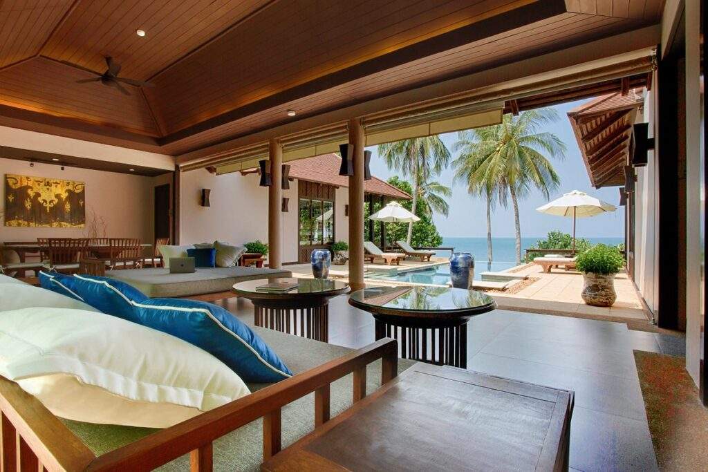 large tropical resort room with huge opening looking at to ocean and palm trees