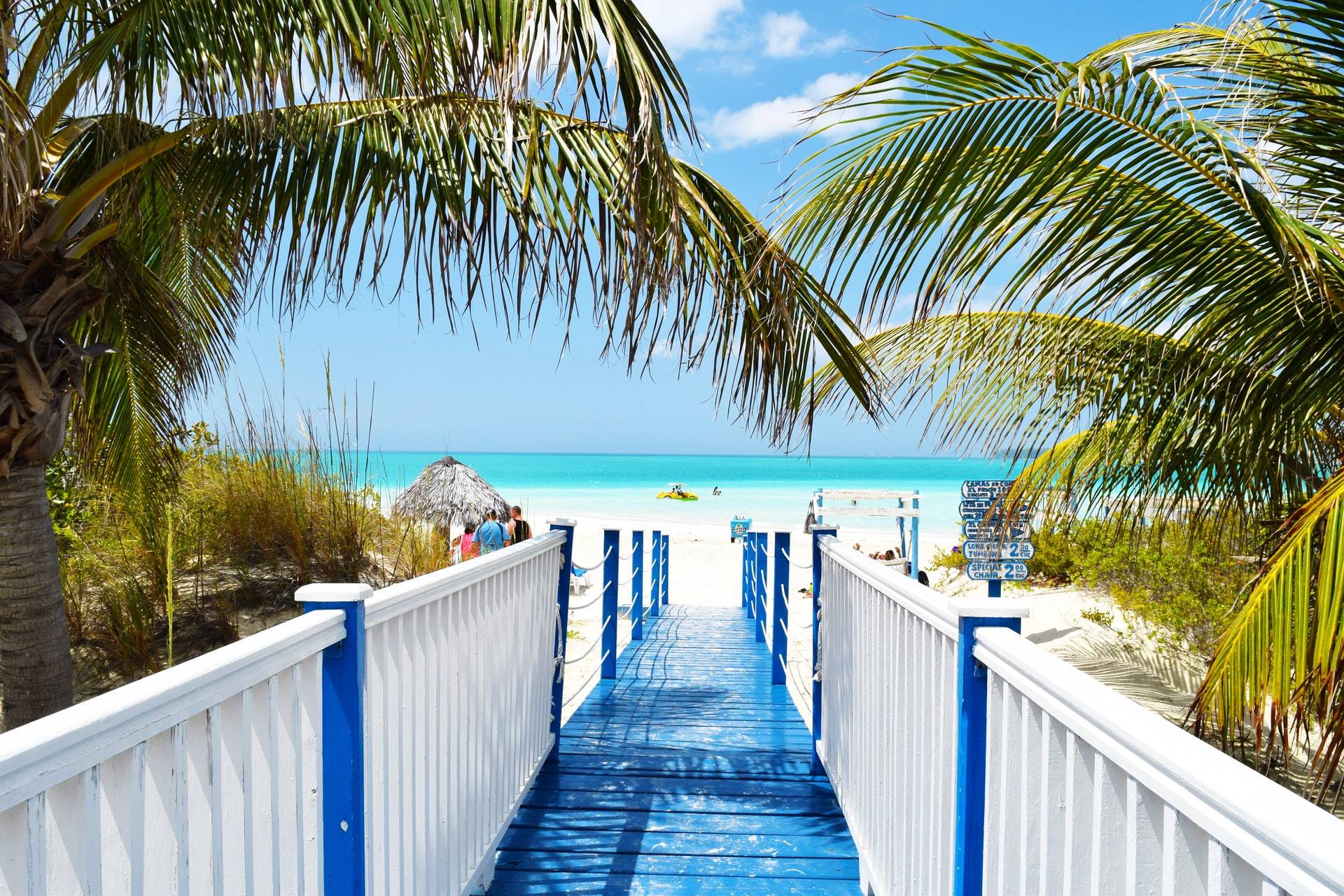 blue wooden walkway leading to beach