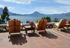 wooden chairs on wood deck looking at mountain across lake
