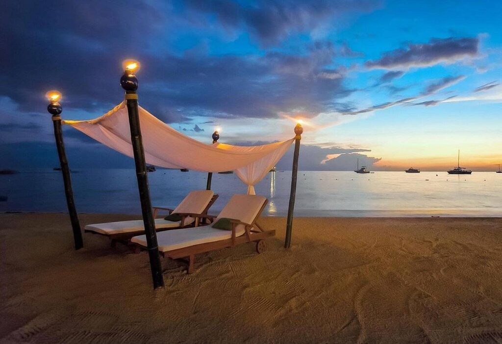 two lounge chairs on beach at sunset
