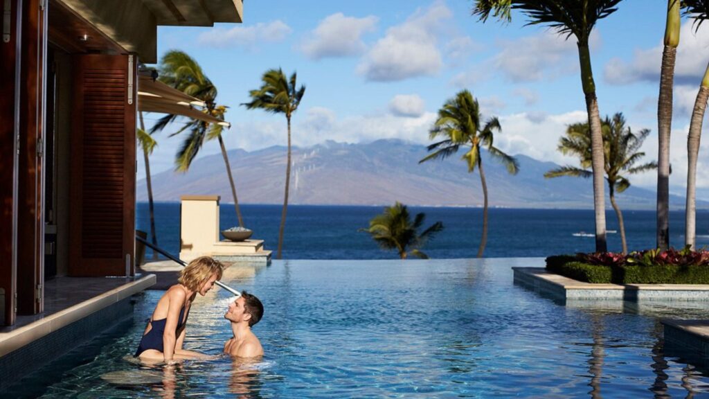 couple in infinity pool with volcano in background